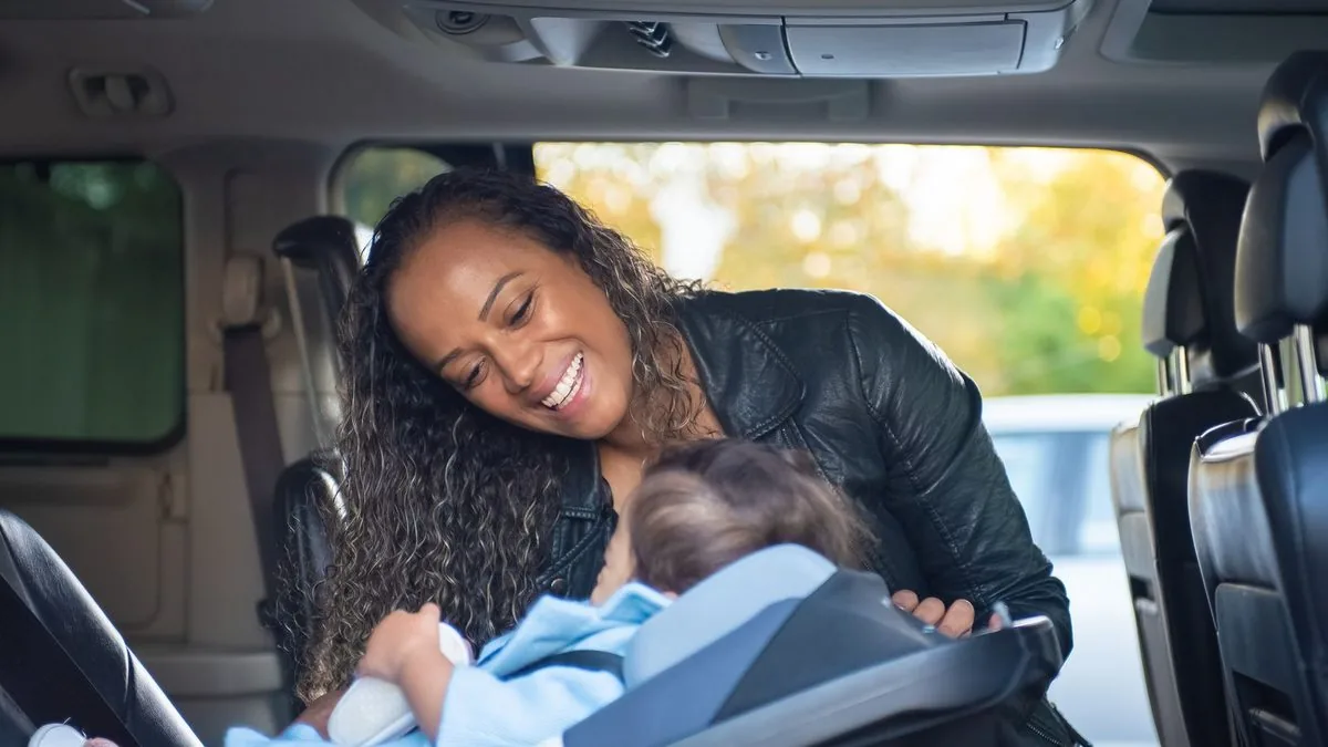 Mãe acomodando o bebê no bebê conforto dentro do carro