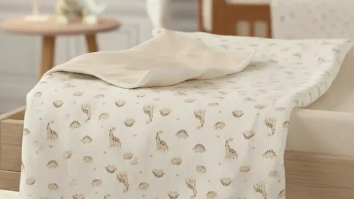 Manta de algodão dupla face estampada estendida sobre uma cadeira de bebê