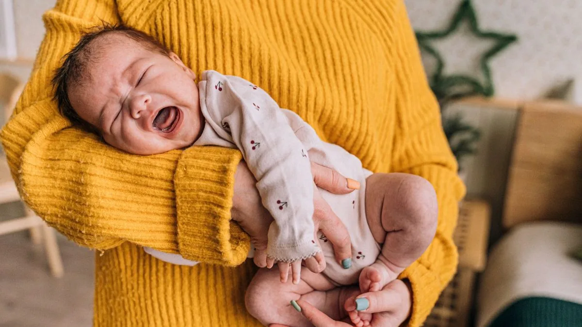 Mãe acalmando no colo o bebê que chora