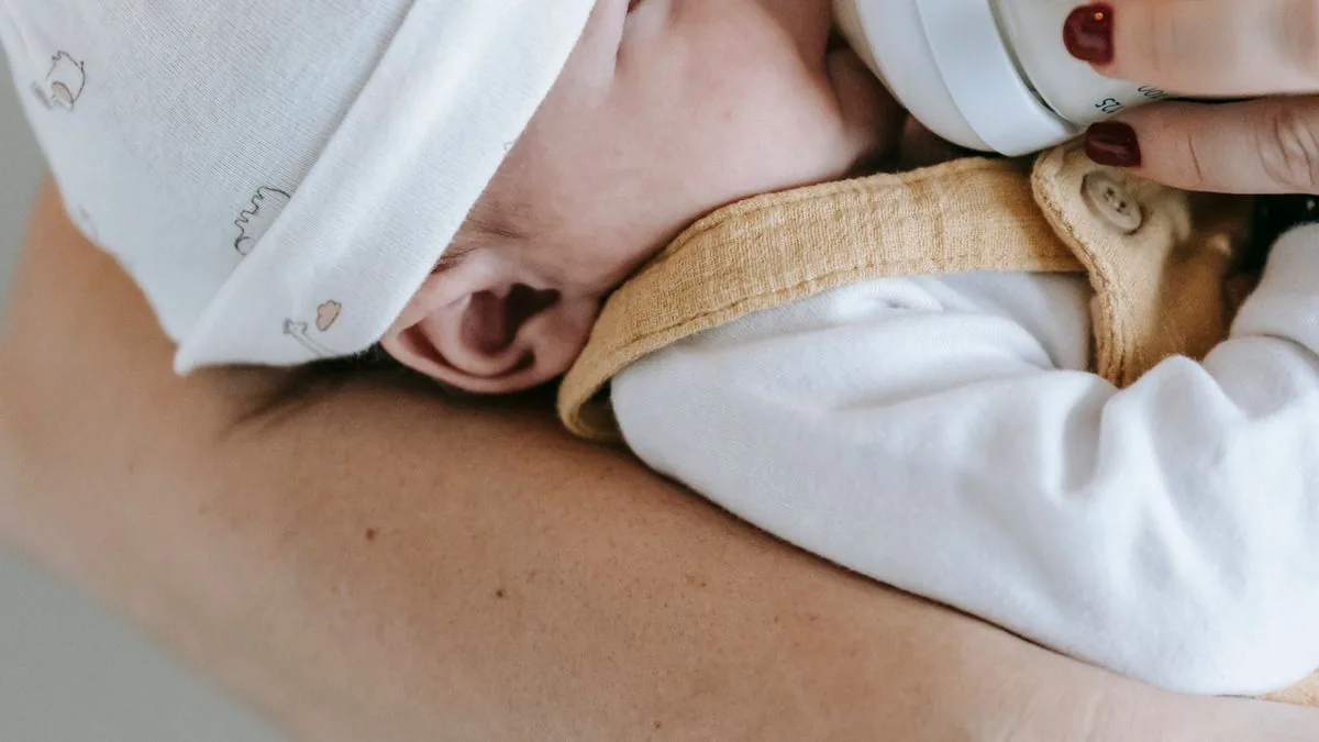 Bebê no colo da mãe mamando na mamadeira
