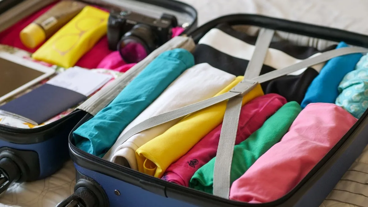 Mala aberta sobre a cama com roupas dobradas e organizadas para a maternidade