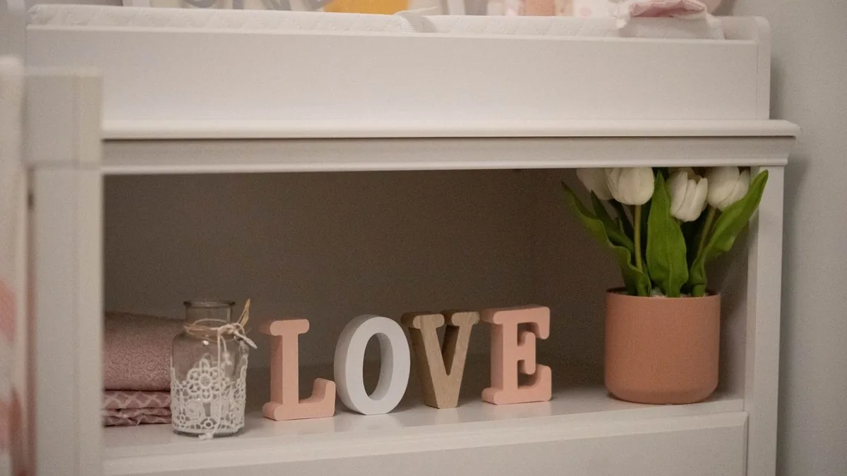 Letras de madeira formando a palavra amor sobre uma prateleira do quarto do bebê