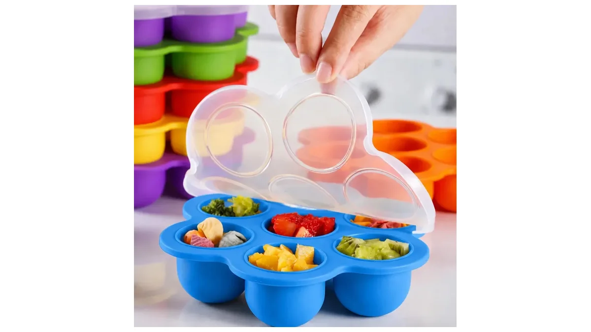 Forma de silicone azul com sete cavidades e tampa transparente cheia de porções de papinha coloridas