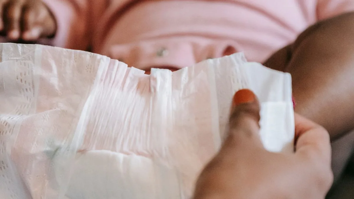 Fralda descartável sendo fechada em um bebê