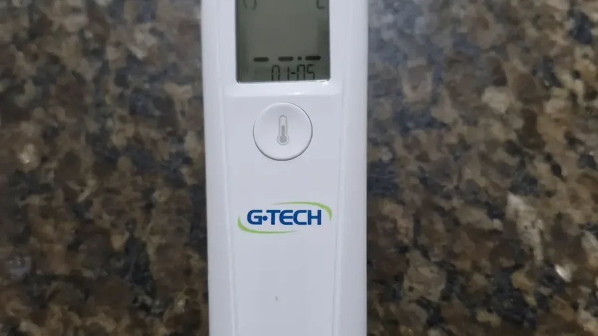Termômetro infravermelho de testa Easy Sensor branco em cima de uma bancada, com o visor aceso