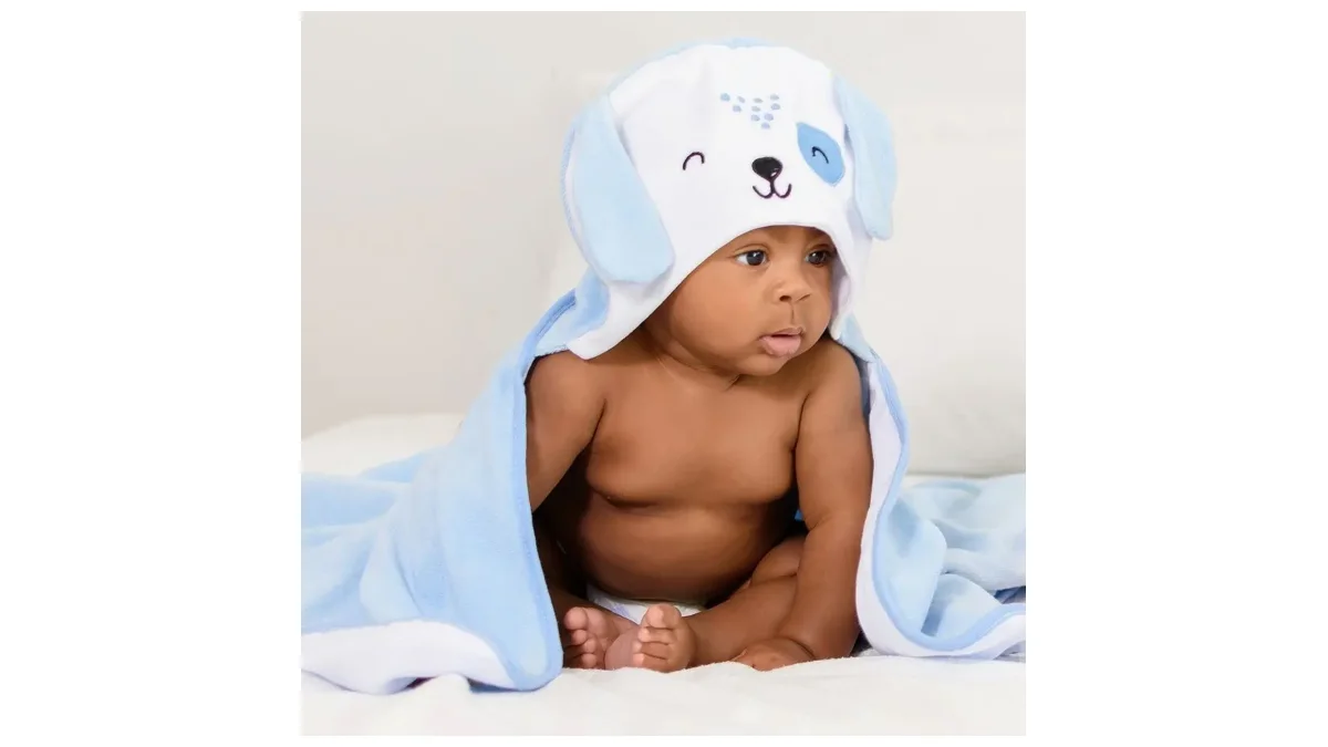 Bebê sentado envolto em toalha forrada azul com capuz de cachorrinho