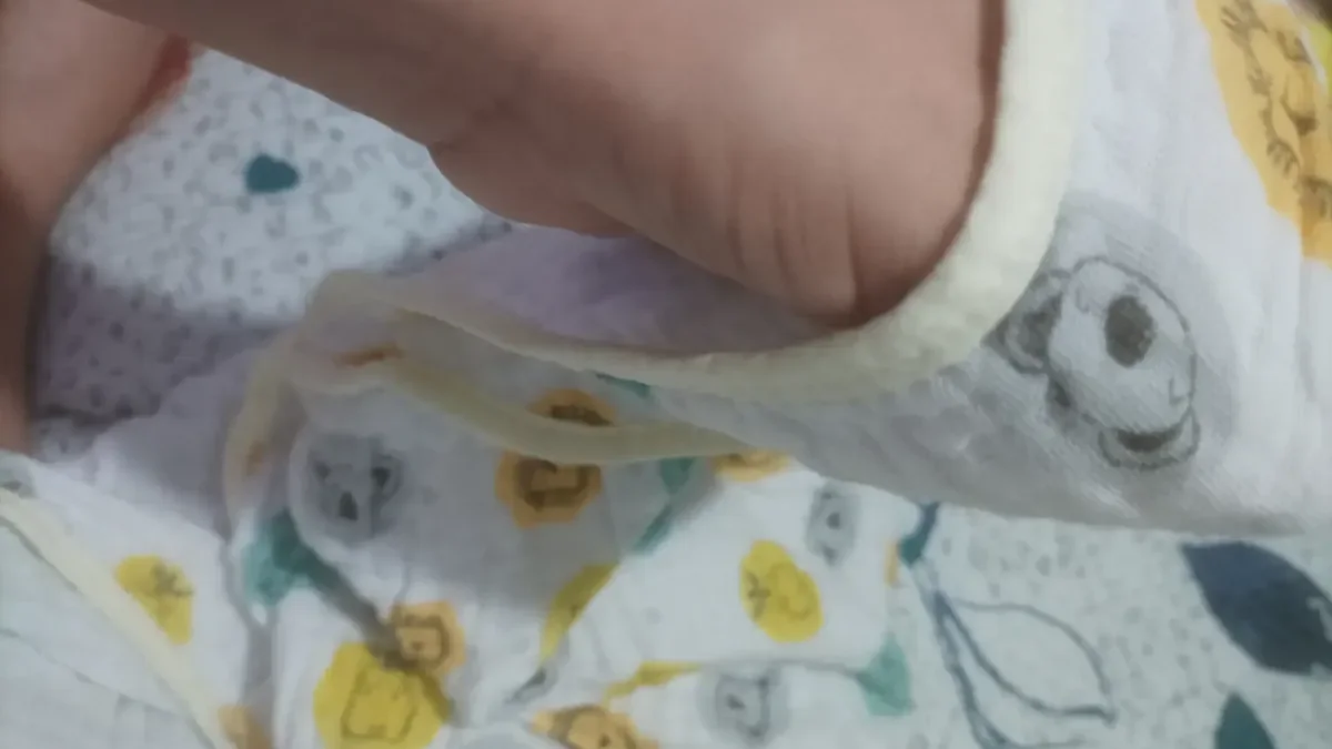 Detalhe do tecido de fralda soft estampado de uma toalha de bebê com viés amarelo